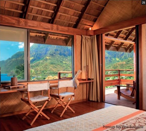 Bungalowzimmer mit Regiestühlen, grossen Fensterfronten und Terrasse mit Blick auf die grünen Berge.
