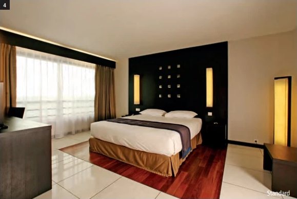 Standardzimmer im Hotel Tahiti Nui mit Doppelbett, dunklem Kopfteil und grosser, verhangener Fensterfront.