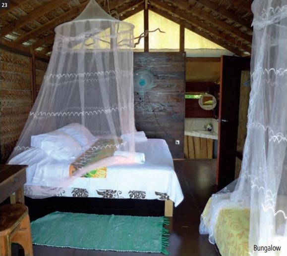 Innenansicht eines Bungalows der Pension Vaiama Village mit Bett unter einem Moskitonetz und einem Dach aus geflochtenem Holz.