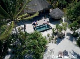 Blick von oben auf eine Villa mit privatem Pool und Liegestühlen, umgeben von Palmen.
