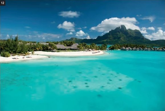 Luftaufnahme des St. Regis Bora Bora Resort mit türkisfarbener Lagune, weissem Sandstrand und dem Mount Otemanu im Hintergrund.