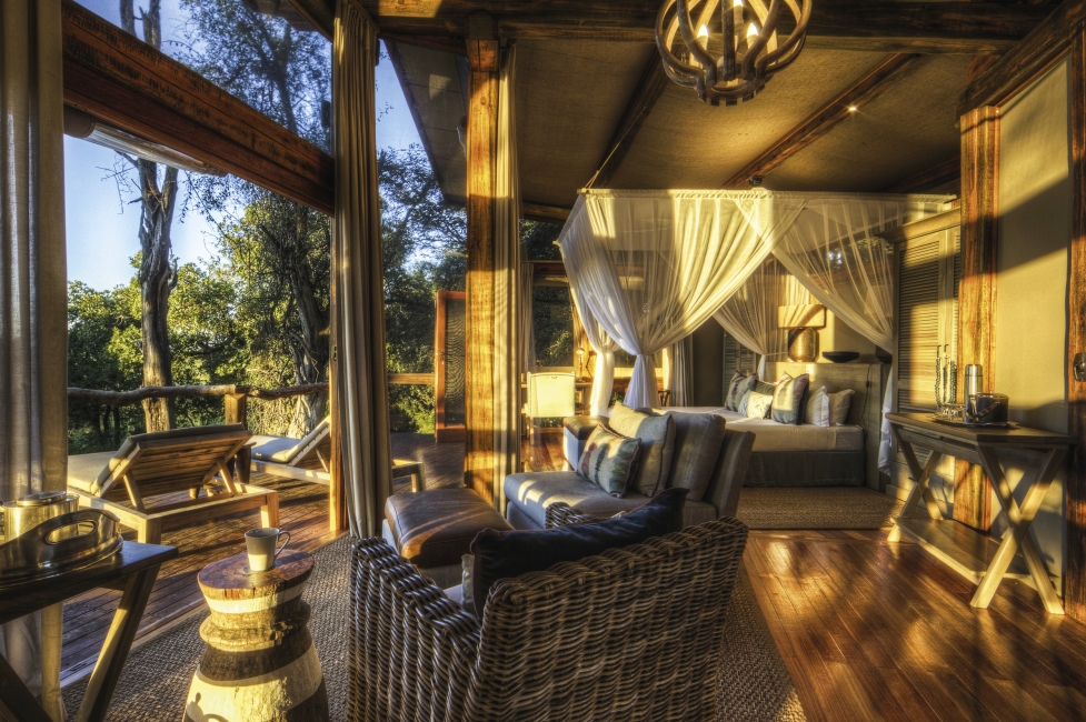 Room with bed and armchair at Camp Okavango